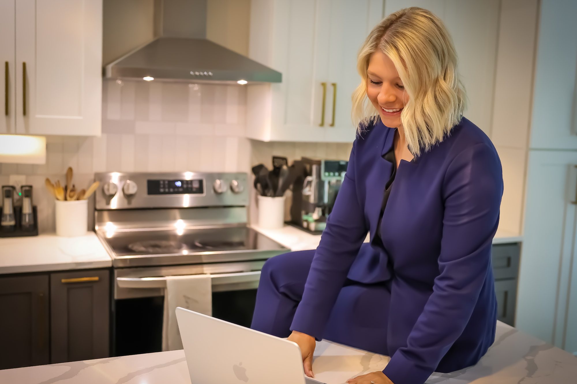 Sara working on a laptop at a kitchen island