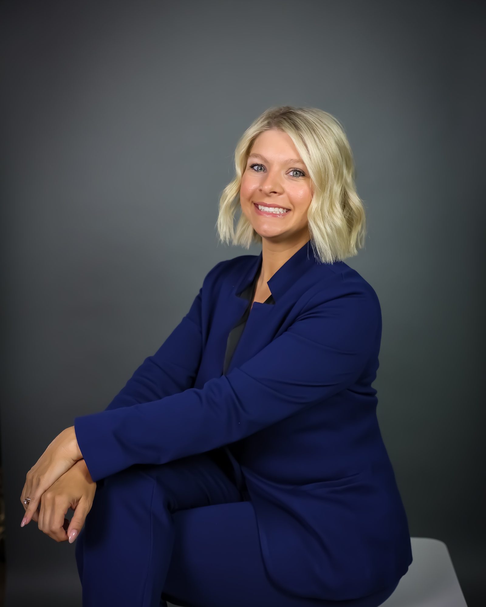 Sara Johnson in a navy suit, seated, studio portrait